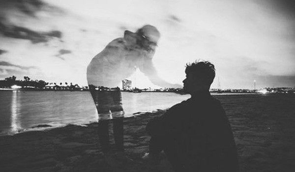 two people are standing on the beach at night