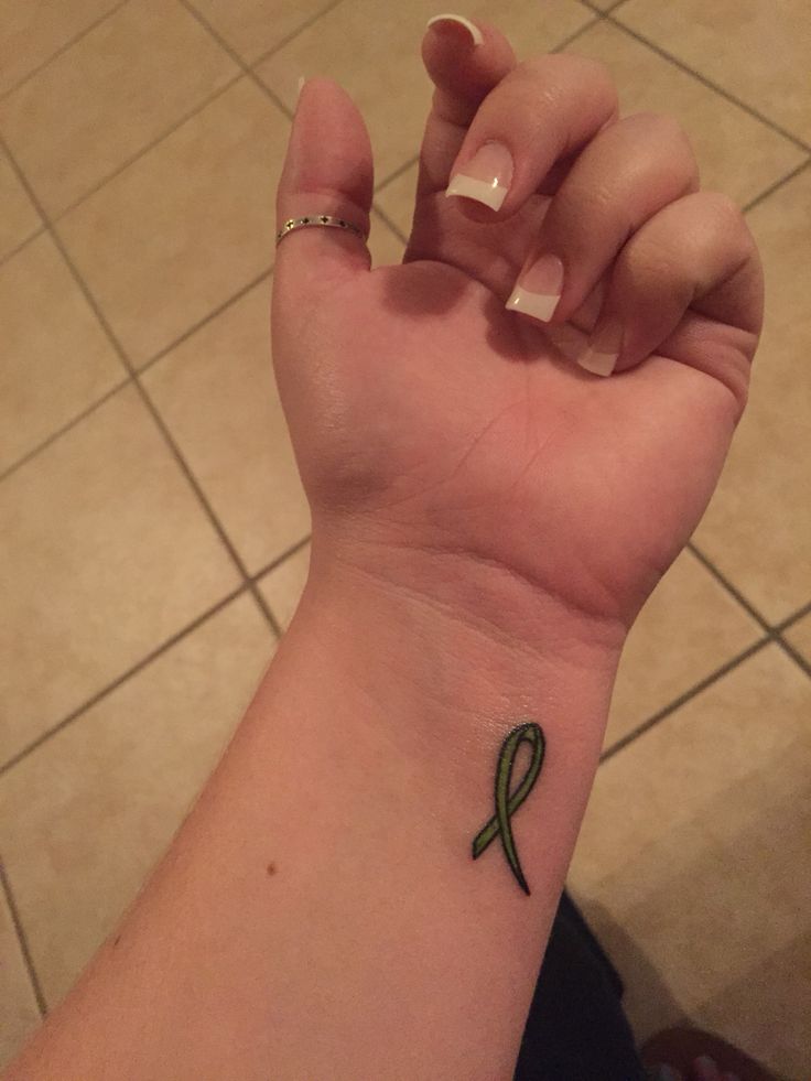 a small green ribbon tattoo on the wrist