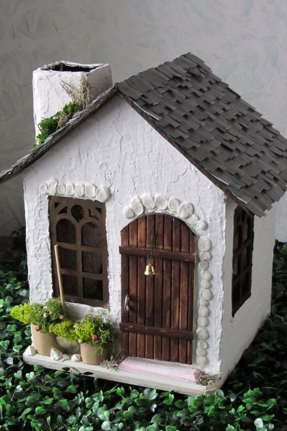 a small white house sitting on top of green plants