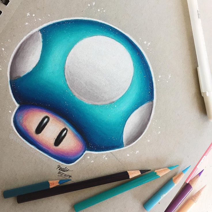 a drawing of a blue mushroom with eyes drawn on paper next to colored pencils