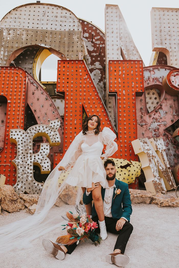 a bride and groom pose in front of the las vegas sign for their elopement