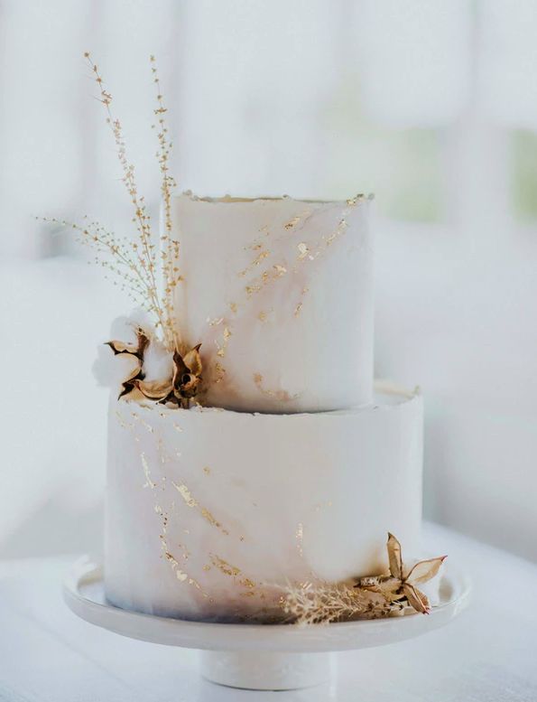 two tiered white wedding cake with dried flowers on top