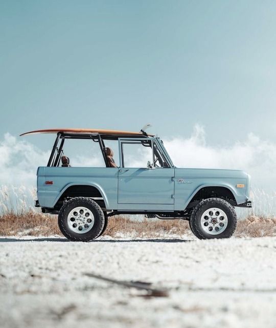 a blue truck with a surfboard on top of it