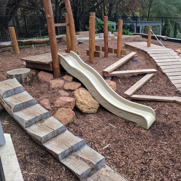 a playground with a slide and wooden steps