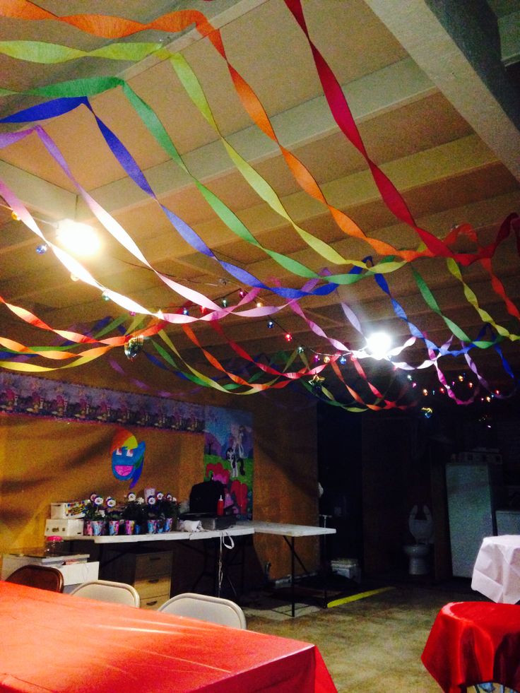 colorful streamers are hanging from the ceiling in a room with red table cloths