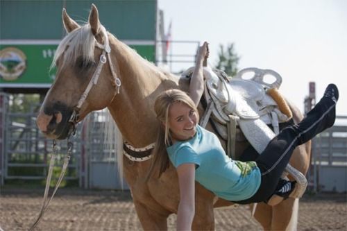 a woman is posing next to a horse