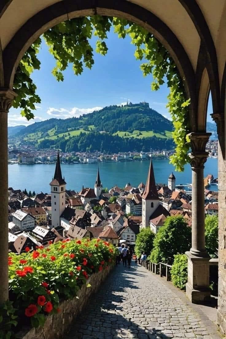 an archway leading to a town with flowers in the foreground