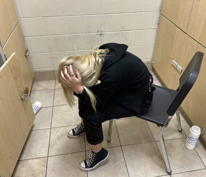 a woman sitting on a chair with her head in her hands while looking at the floor