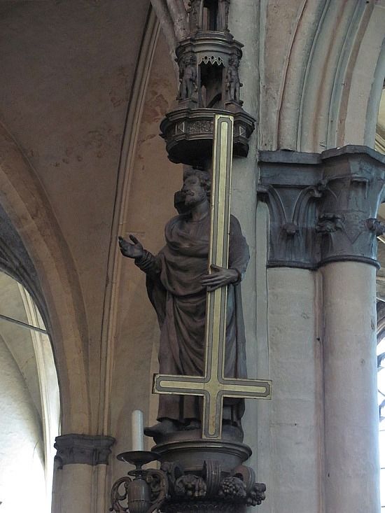 a statue in the middle of a church with a cross hanging from it's side