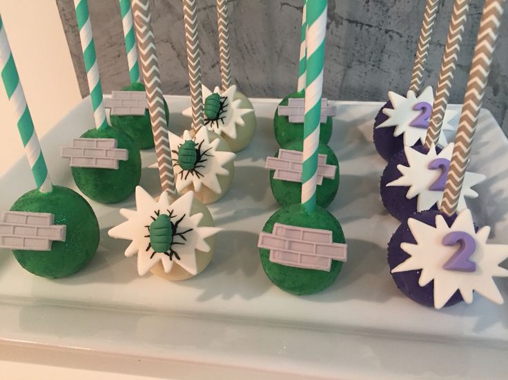 some green and white cake pops are on a table with candles in the shape of snowflakes