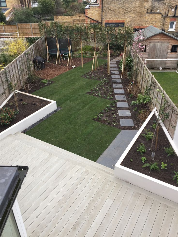 a backyard with wooden decking, grass and small garden area in the back yard