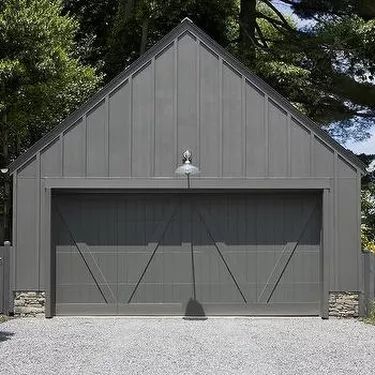 a gray garage with two doors on the front and one door open to let in light