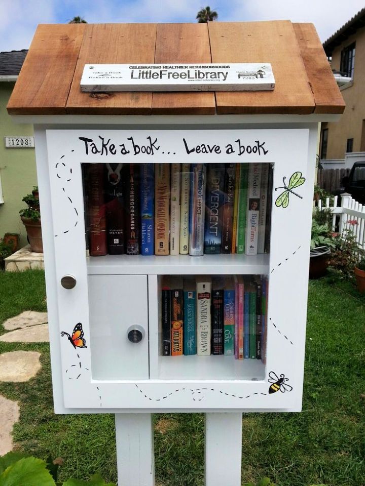 there is a bookcase that has books on it in the grass and some plants