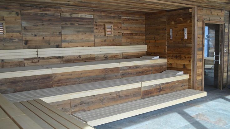 two wooden benches sitting next to each other in front of a wall made out of wood planks