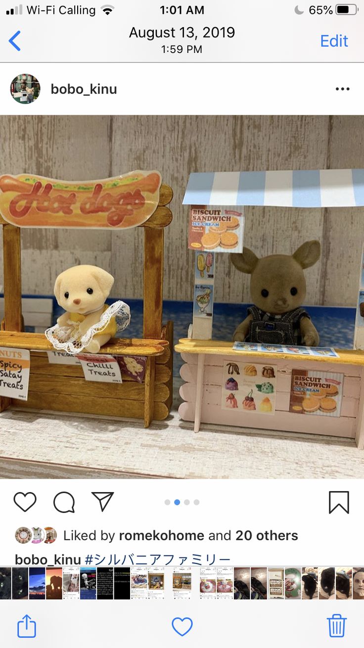 two teddy bears sitting on top of a wooden bench next to each other in front of a sign