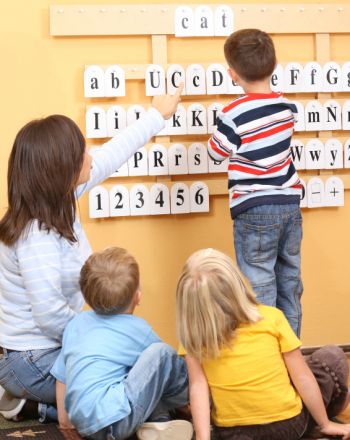 three children are sitting on the floor and playing with scrabble tiles in front of them