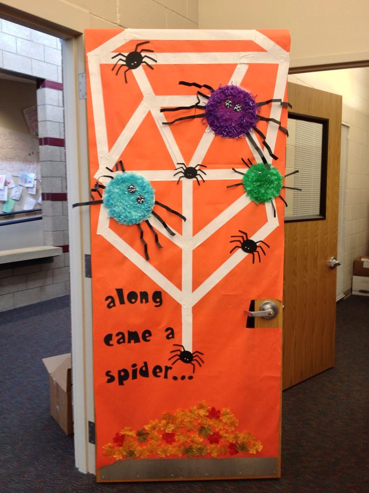 an orange door decorated with paper flowers and spider's on the outside, says along came a spider