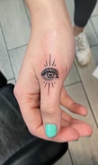 a person's hand with a small tattoo on the middle finger and an all seeing eye