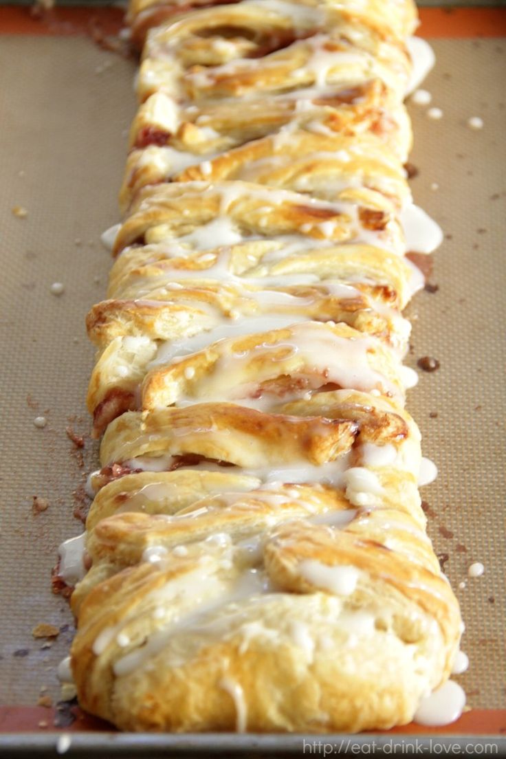 a long pastry with white icing sitting on top of a baking sheet