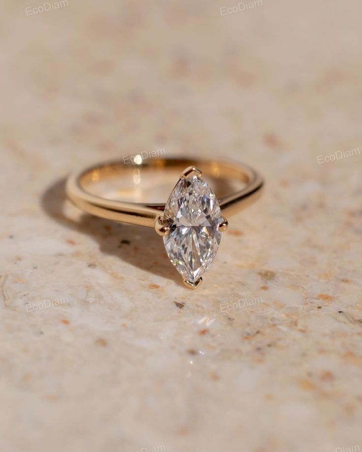 a close up of a diamond ring on a marble counter top with the center stone missing