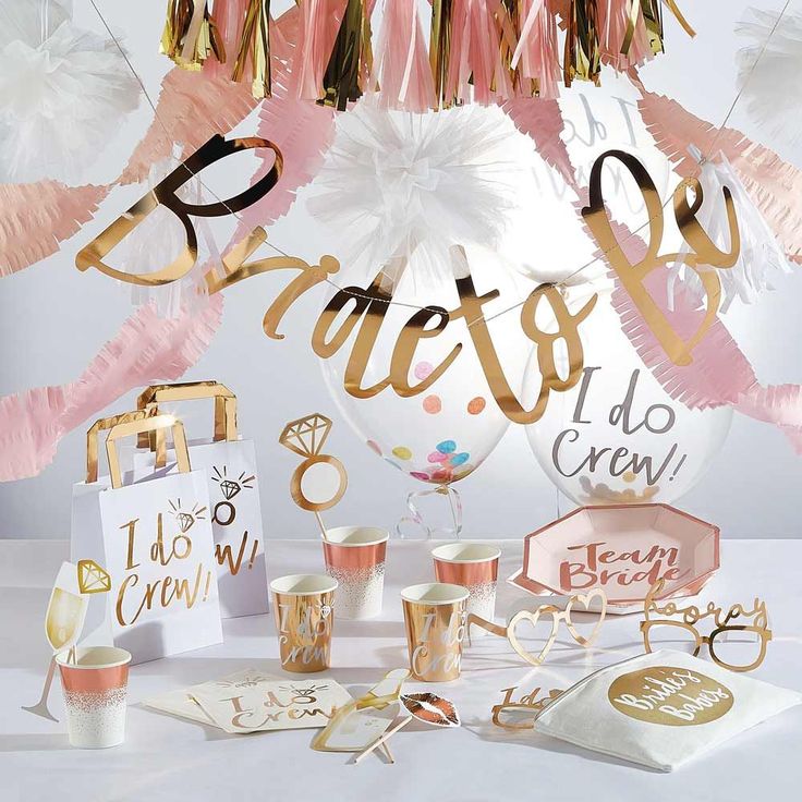 a table topped with lots of pink and gold party supplies on top of a white table