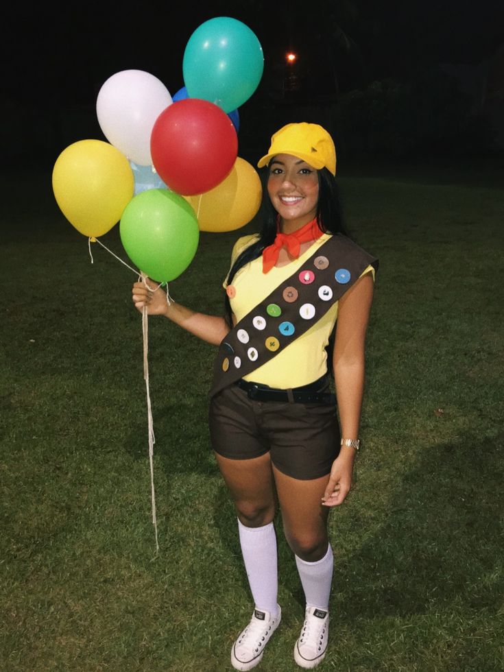 a woman is holding some balloons in her hand and posing for the camera at night