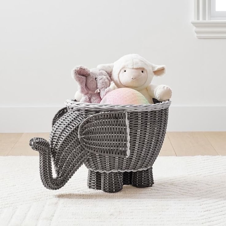 an elephant basket with stuffed animals in it on a white rug next to a window