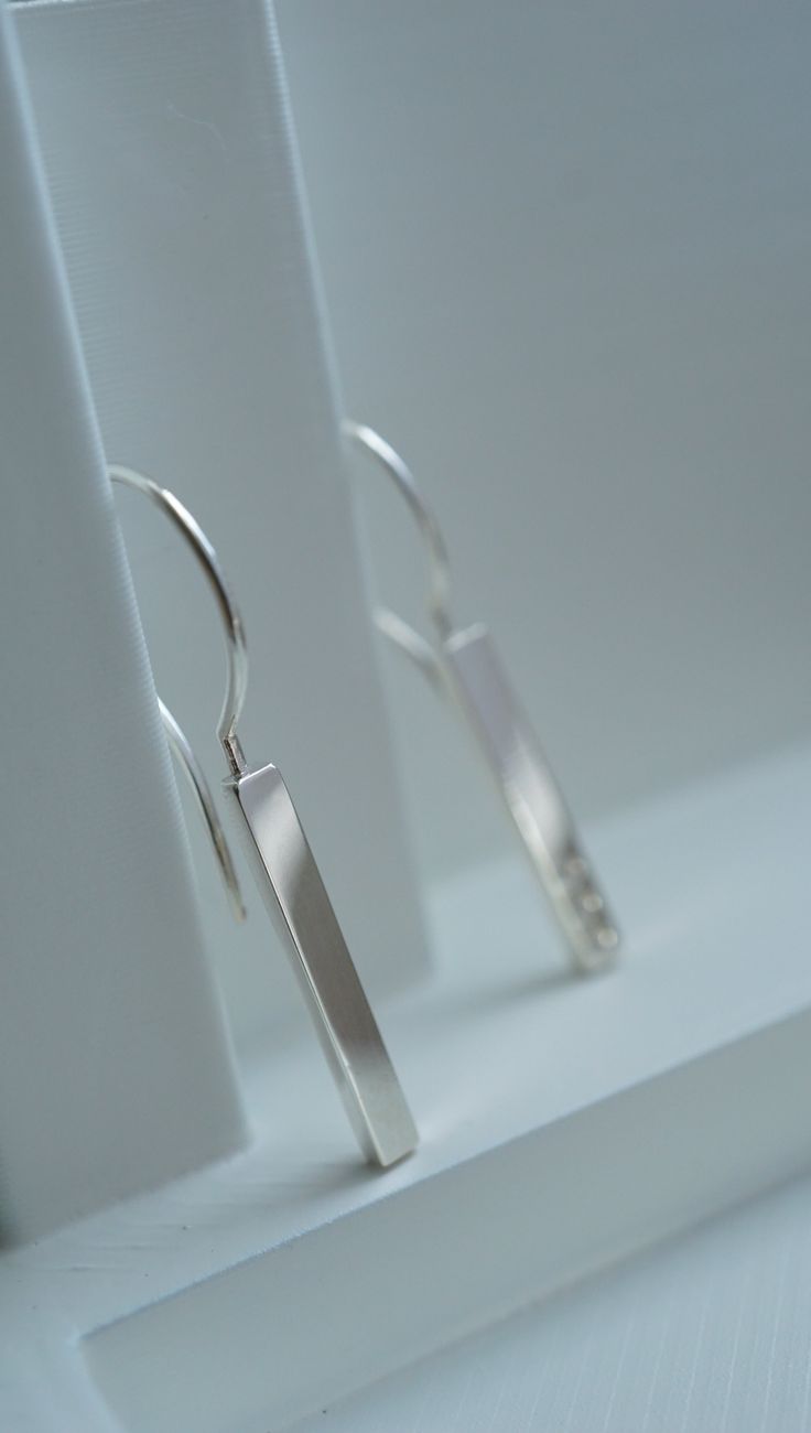 Ellipsis earrings are made of Sterling silver .925 Minimalist mirror polished elegant earrings with an asymmetrical feature. The ellipsis character is deliberately imprinted on one earring only. The earrings may be complemented with the Ellipsis ring which is performed in the same technique and style. The design symbolises the wisdom of withholding your thoughts from those who are not willing to listen and genuinely understand you. Minimalist Oblong Earrings For Formal Occasions, Minimalist Polished Silver Earrings, Modern Oblong Single Earring Jewelry, Modern Polished Finish Linear Earrings For Gift, Modern Silver Linear Earrings As Gift, Minimalist Sterling Silver Oblong Jewelry, Formal Minimalist Oblong Earrings, Silver Minimalist Polished Earrings, Minimalist Sterling Silver Linear Earrings For Formal Occasions