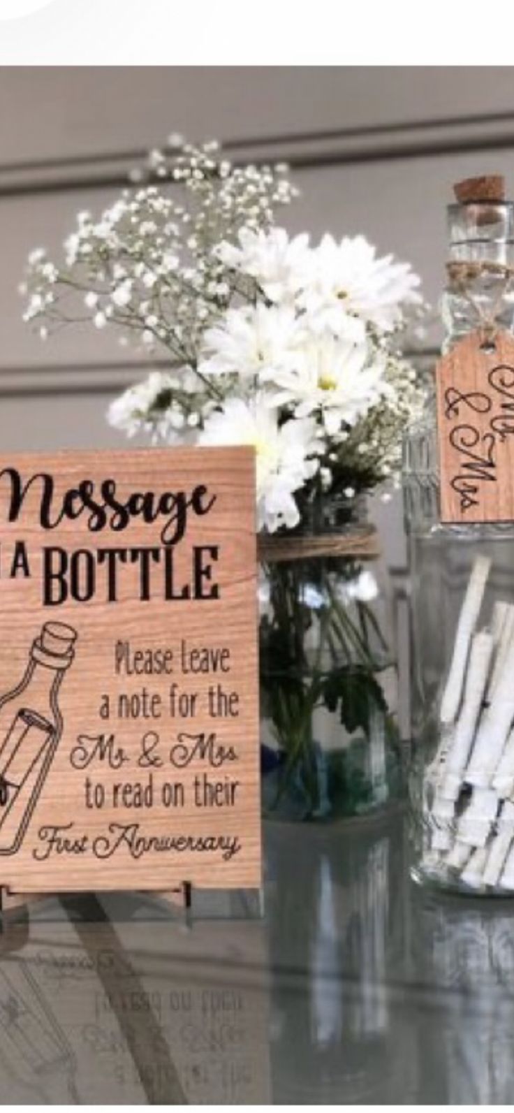 two wooden signs sitting on top of a table next to vases filled with flowers