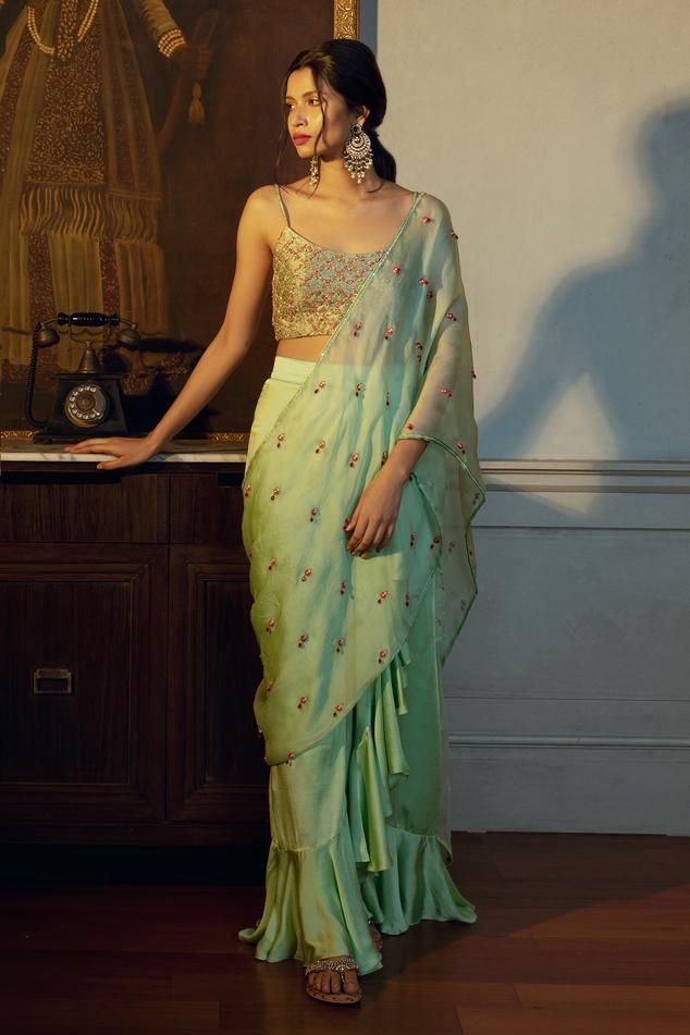 Light green pre-draped concept saree with tear drop beads butti embellishments and ruffle saree skirt hem. Paired with an embroidered brocade noodle strap padded cami blouse.
Components: 2
Pattern: Embroidery
Type Of Work: Beads
Neckline: Round Neck
Sleeve Type: Noodle Strap
Fabric: Blouse: Brocade Silk 
Saree Skirt: Cotton Satin
Pallu: Satin Organza   
Color: Green
Other Details: 

Model height: 5 ft 8 inches, wearing size XS
Closure: 
Blouse : Side zipper
Saree Skirt: Side hook with zipper
Len Noodle Strap Blouse, Concept Saree, Saree Skirt, Noodle Strap, Brocade Saree, Ruffle Saree, Drape Saree, Beaded Neckline, Pattern Embroidery