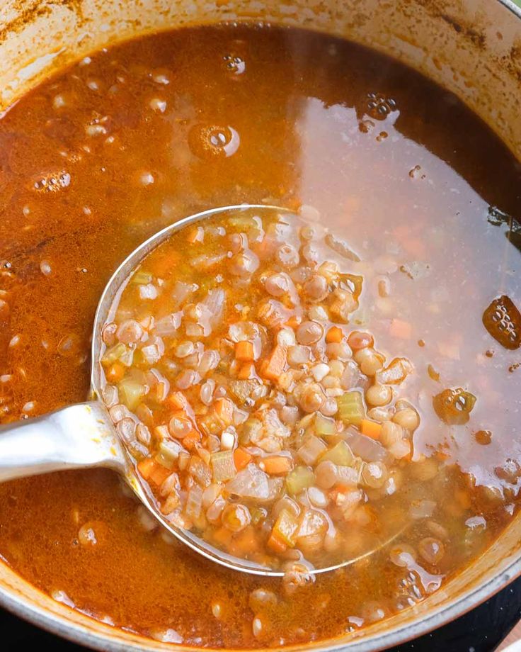 a ladle full of beans and carrots cooking in a pot