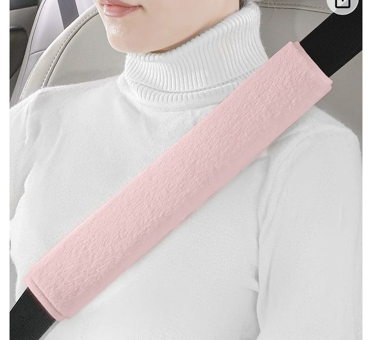 a woman wearing a pink seat belt in the back of a car with her head resting on an arm rest