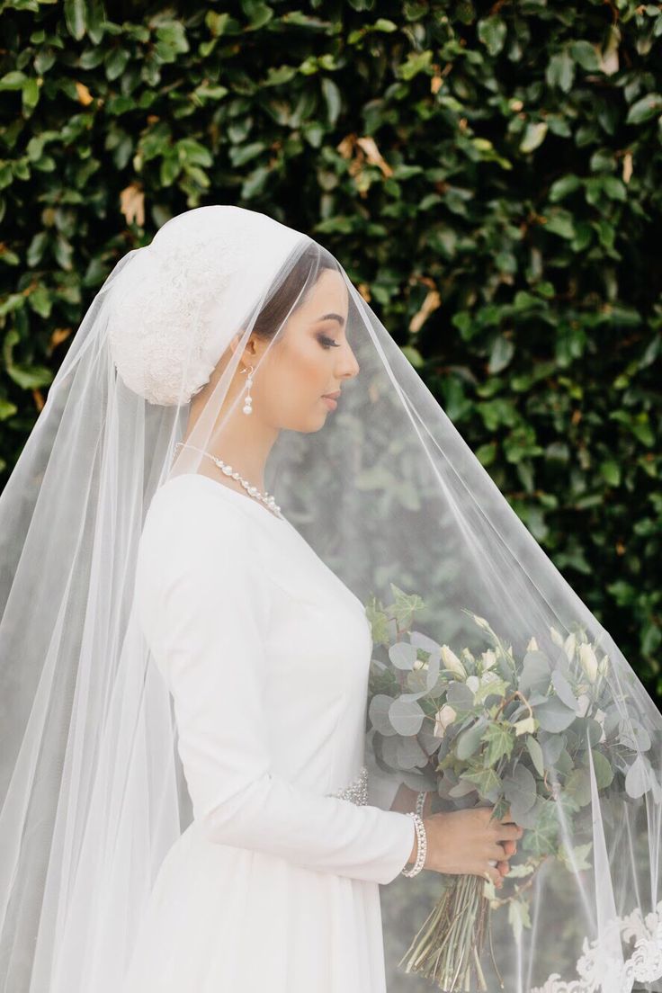 a woman wearing a veil and holding flowers