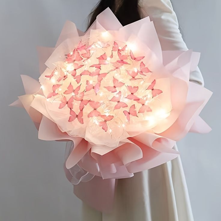 a woman holding a bouquet of flowers with lights on it's petals in the shape of butterflies