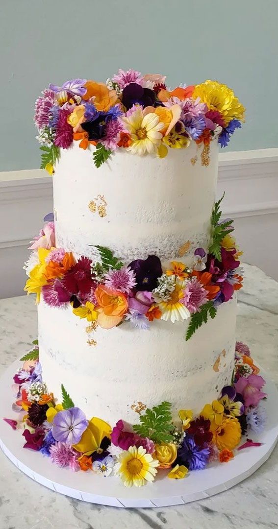 a three layer white cake with colorful flowers on top