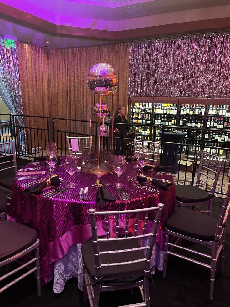 the table is set up with purple linens and silver chairs for an elegant event