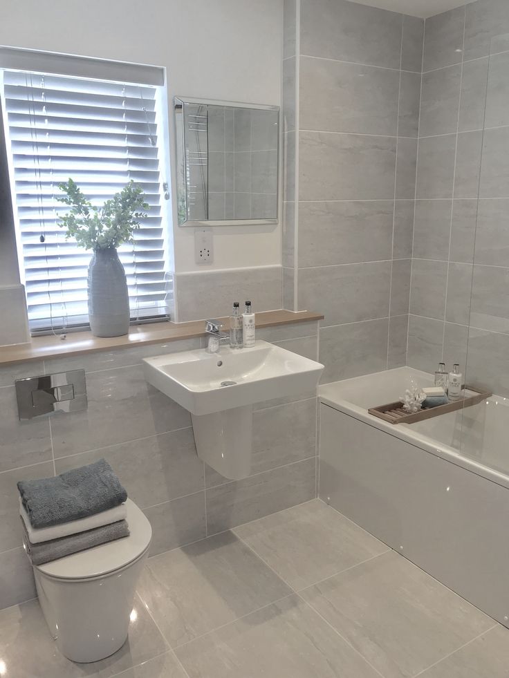 a bathroom with a toilet, sink and bathtub next to a window in it