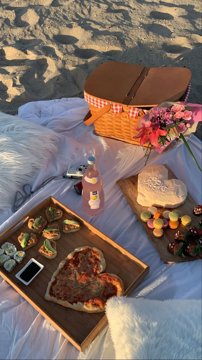 a pizza and other food on a blanket at the beach