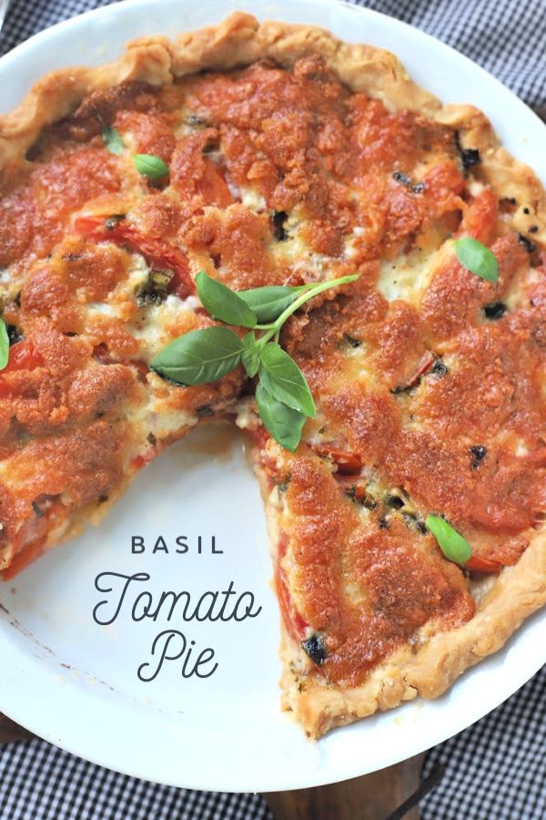 a deep dish pizza with basil and tomato sauce on a white plate, ready to be eaten