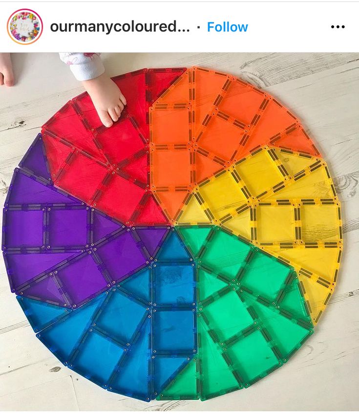 a child's hand on top of a rainbow colored piece of paper