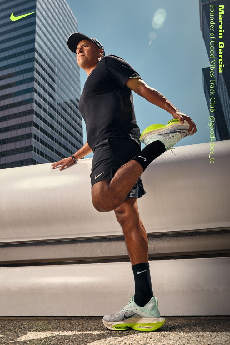 a man in black shirt and shorts holding a tennis racquet next to tall buildings