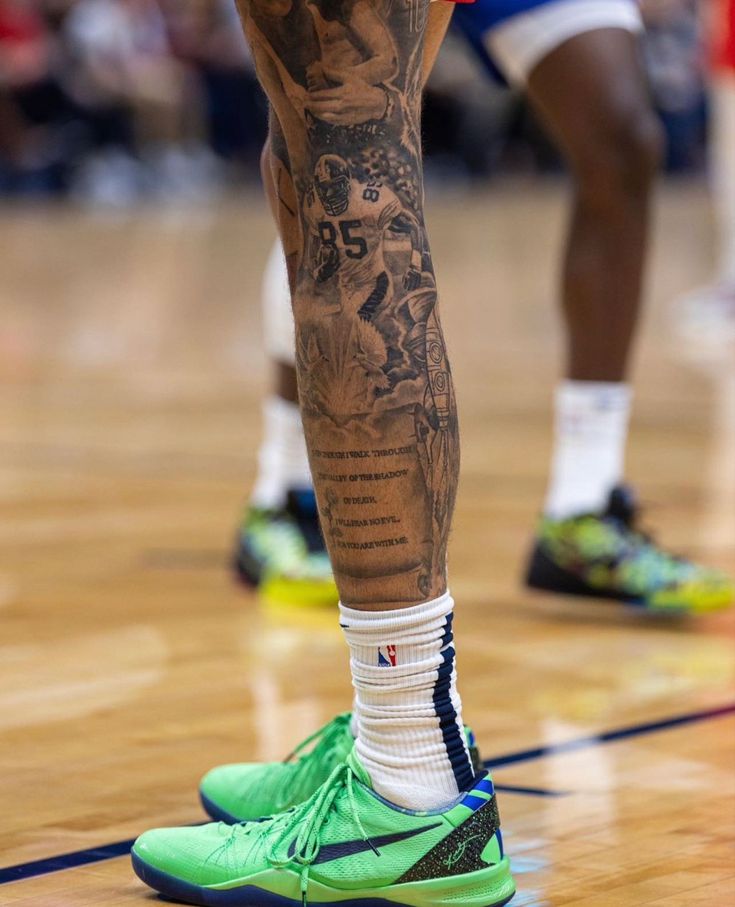 the legs and ankles of a basketball player with tattoos on his arms, wearing green shoes