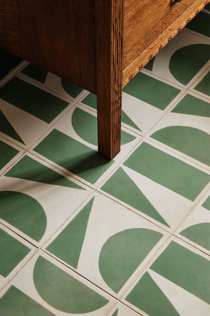 a close up of a green and white tile floor with a wooden table in the background