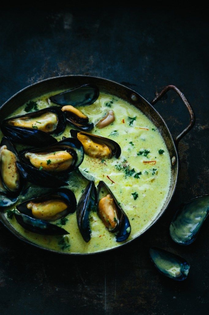 a pan filled with mussels and sauce on top of a table