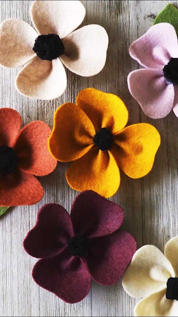 several different colored felt flowers sitting on top of a wooden table