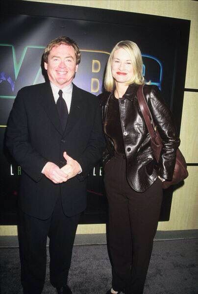 a man and woman standing next to each other in front of a wall with an advertisement on it