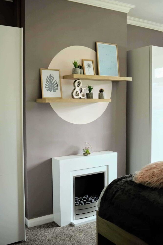 a bed room with a neatly made bed and a shelf on the wall above it