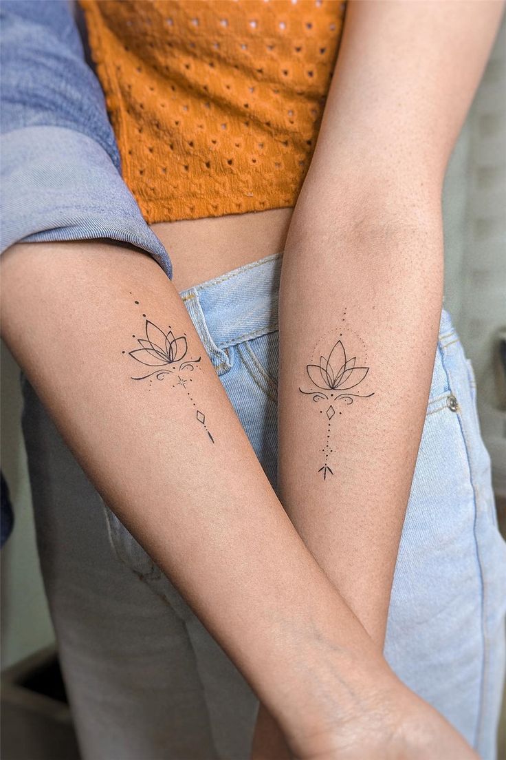 two people with matching tattoos on their arms, one holding the other's arm