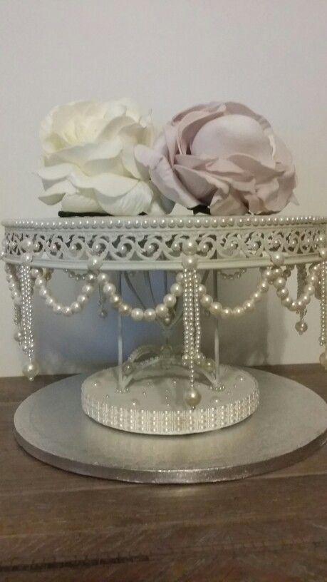 there is a silver tray with flowers on it and pearls around the edges, as well as beaded trim