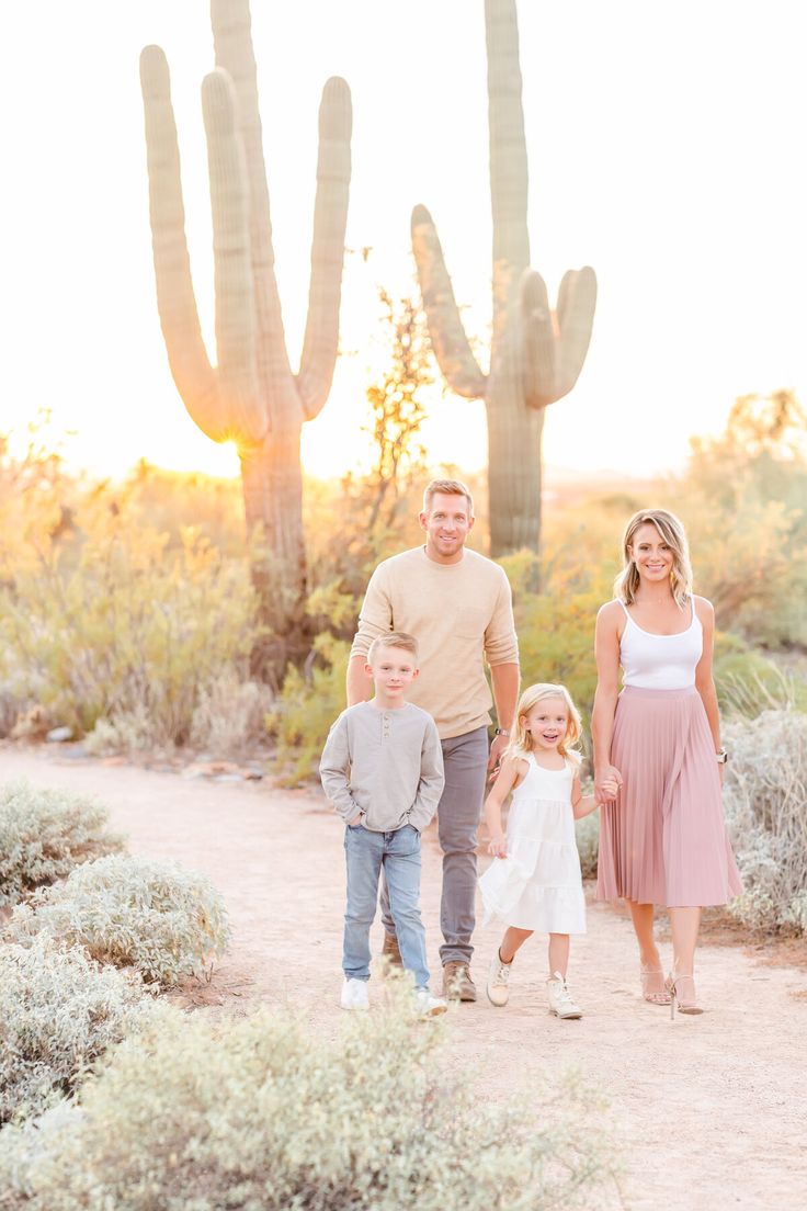 a family walking in front of a cactus at sunset